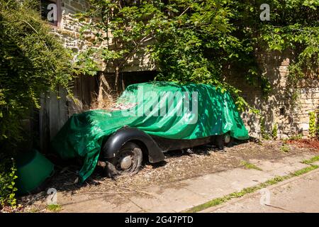 vieille voiture abandonnée recouverte de bâche verte Banque D'Images