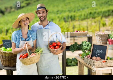 Portrait d'un couple souriant tenant des légumes frais dans des paniers Banque D'Images