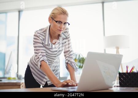 Cadre attentif utilisant un ordinateur portable au bureau Banque D'Images