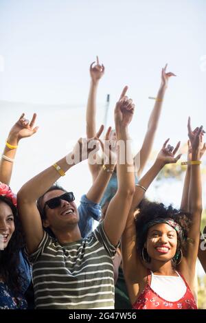 Des fans heureux dansant avec les armes levées pendant le festival de musique Banque D'Images