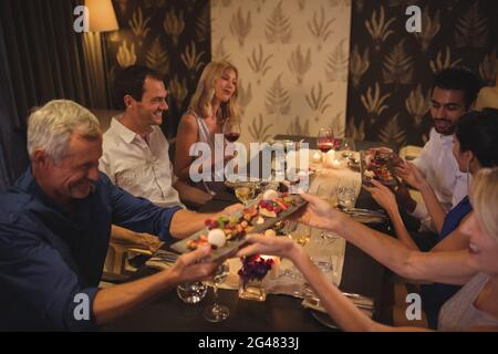 Des amis heureux qui interagissent entre eux tout en dînant Banque D'Images