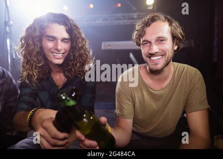 Portrait d'amis souriants qui toaster les bouteilles de bière Banque D'Images