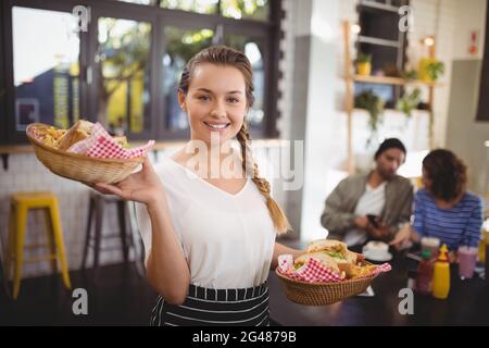 Portrait d'une jeune serveuse souriante transportant de la nourriture dans des paniers en osier Banque D'Images