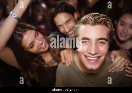 Portrait d'un homme heureux avec des amis à la discothèque Banque D'Images