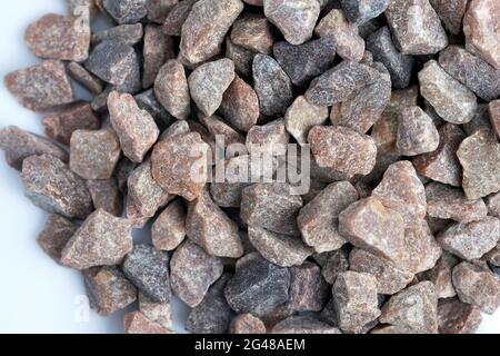 Quartzite rouge sur fond blanc vue de dessus. Copeaux de pierre décoratifs pour l'aménagement paysager. Gros plan sur la pierre concassée. Banque D'Images