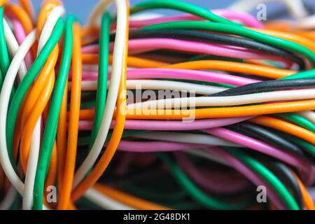 Un faisceau de fils électriques multicolores, voiture, ordinateur, téléphone tordus ensemble. Câbles orange, vert, rose, blanc sur fond gris Banque D'Images