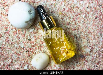 Essence de sérum d'huile jaune dans un flacon en verre platly. Huile solaire pour protéger le visage et le corps les jours d'été. Thème de la mer, coquillages, pierres, sable rose. Conc Banque D'Images