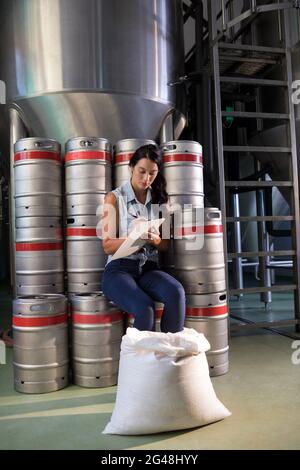 Travailleur féminin writing on clipboard in factory Banque D'Images