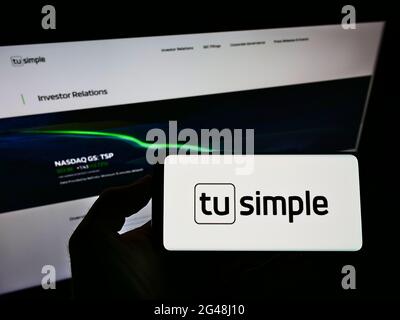 Personne tenant un smartphone avec le logo de la compagnie de conduite autonome des États-Unis TuSimple Holdings Inc. À l'écran devant le site Web. Mise au point sur l'affichage du téléphone. Banque D'Images