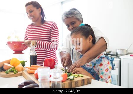 Grand-mère aidant la petite-fille à hacher des légumes dans la cuisine Banque D'Images