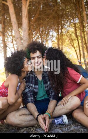 Les femmes embrassent de jeunes amis masculins assis sur le terrain Banque D'Images