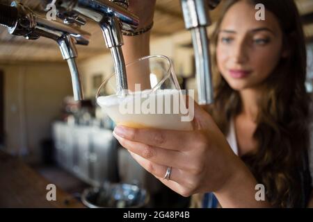 Gros plan de la barmaid qui verse de la bière du robinet dans un verre Banque D'Images