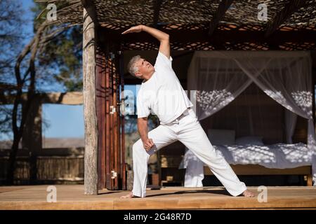 Homme pratiquant le yoga en chalet Banque D'Images