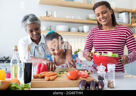 Grand-mère aidant la petite-fille à hacher des légumes dans la cuisine Banque D'Images