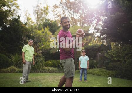 Homme jouant au rugby avec la famille au parc Banque D'Images