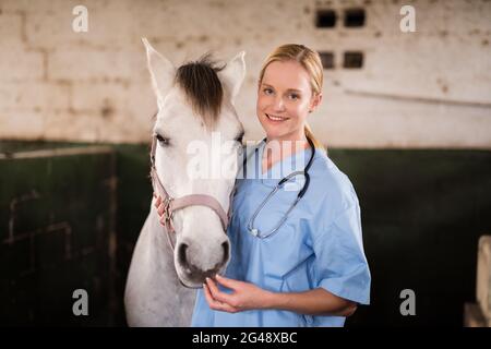 Portrait de femme souriante vétérinaire debout à cheval Banque D'Images