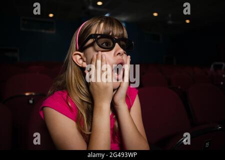 Une fille surprise portant des lunettes 3D tout en regardant un film Banque D'Images