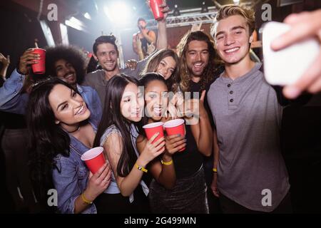 Des amis heureux prenant le selfie à un concert de musique Banque D'Images