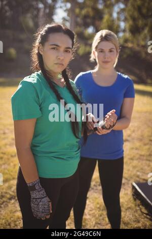 Portrait d'une femme aidant son ami à porter un groupe de boxe Banque D'Images