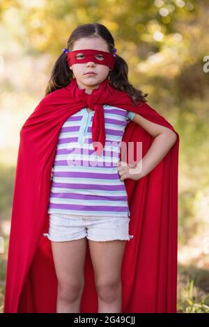 Petite fille confiante portant un costume de super-héros au camping Banque D'Images