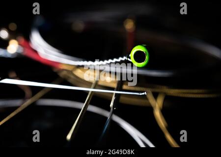 Macro gros plan de Green ball fin de Metal Acoustic Guitar String avec pile de cordes en arrière-plan Banque D'Images