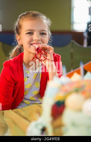 Jolie fille soufflant corne de fête pendant la fête d'anniversaire Banque D'Images