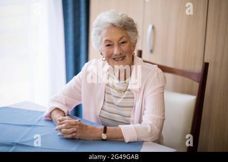 Portrait d'une femme âgée souriante assise avec les mains jointes Banque D'Images