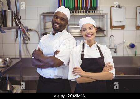 Deux chefs debout avec les armes croisées dans la cuisine commerciale Banque D'Images