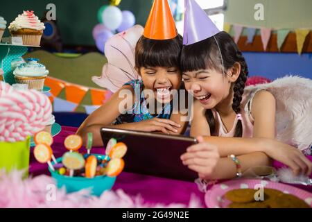 Enfants utilisant une tablette numérique pendant la fête d'anniversaire Banque D'Images