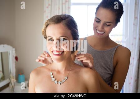 Demoiselle d'honneur attachant bride collier dans la chambre Banque D'Images