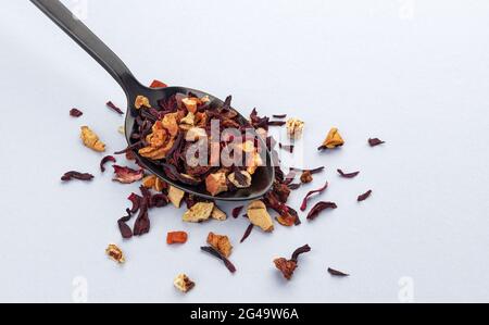 Feuilles de thé aux fruits dans une cuillère sur fond blanc Banque D'Images