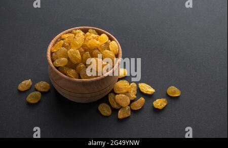 Raisins jaunes dans un bol en bois sur fond noir Banque D'Images