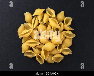 Corgigate de Conchiglie. Pâtes à la coque à rayures brutes sur fond noir, vue du dessus Banque D'Images