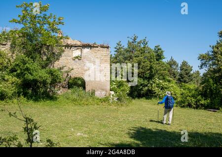 Homme avec sac à dos en admirant les ruines de la vieille maison dans la campagne. Podere Montebello, Modigliana, Forlì, Emilia Romagna, Italie, Europe. Banque D'Images