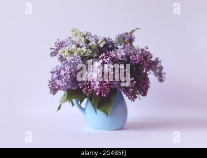 Magnifique bouquet de fleurs violettes parfumées dans un vase en céramique bleue sur fond clair. Plante de Syringa vulgaris ou lilas. Banque D'Images