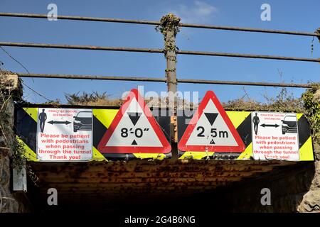 Signes de distanciation sociale sur un pont ferroviaire bas au-dessus d'un tunnel étroit partagé par les piétons et les véhicules à moteur. Banque D'Images