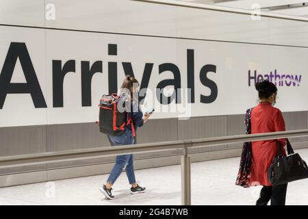 Voyageurs au hall des arrivées internationales avec sac à dos et sacs à main, regardant son mobile à l'aéroport de Londres Heathrow, Angleterre, Royaume-Uni Banque D'Images