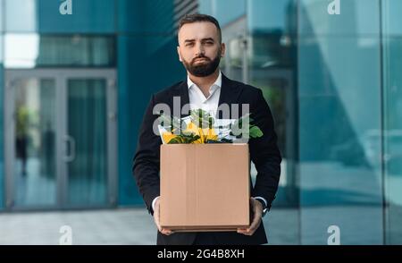 Portrait d'un homme d'affaires désespéré furieux renvoyé en costume debout à l'extérieur avec boîte de substance. Un employé de bureau a perdu son emploi Banque D'Images