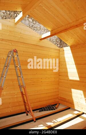 L'intérieur d'une petite cabine préfabriquée en bois partiellement construite sur une base en béton. Les poutres murales sont en place et le toit est presque complet. Banque D'Images