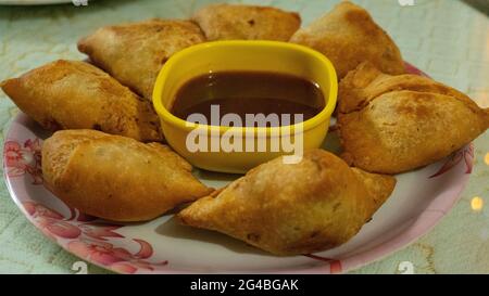 C'est un plat indien appelé samosa qui est servi sur une assiette blanche avec sauce Banque D'Images