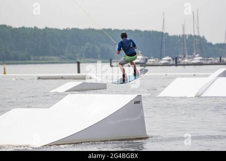 Rostock, Allemagne. 20 juin 2021. Un wakeboarder saute sur la rivière Warnow à l'IGA Park Rostock. L'installation de wakeboard à 6 mâts du parc aquatique d'IGA Park est le premier du genre dans le Mecklembourg-Poméranie-Occidentale et le premier parc aquatique dans une rivière en Europe. Ce week-end marque le début des vacances d'été dans le Mecklembourg-Poméranie-Occidentale. Credit: Frank Hormann/dpa/Alay Live News Banque D'Images