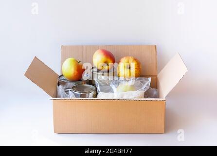 Boîtes de conserve, fruits frais aux pommes, sarrasin et riz dans une boîte en carton. Don d'aliments, thème de livraison. Banque D'Images