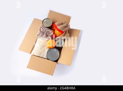 Boîtes de conserve, fruits frais aux pommes, sarrasin et riz dans une boîte en carton. Don d'aliments, thème de livraison. Banque D'Images