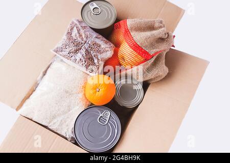 Boîtes de conserve, fruits frais aux pommes, sarrasin et riz dans une boîte en carton. Don d'aliments, thème de livraison. Banque D'Images
