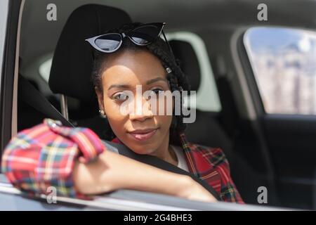Femme afro-américaine se détendant à l'intérieur de sa voiture : concentration sélective et gros plan. Concept de conduite et de loisirs. Banque D'Images