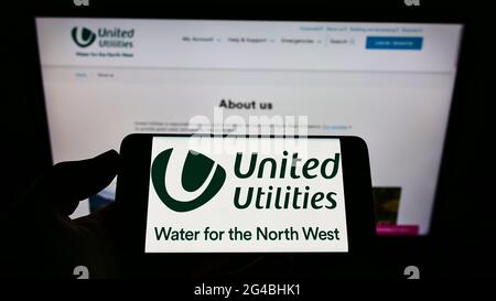 Personne tenant un téléphone portable avec le logo de la société britannique de l'eau United Utilities Group plc à l'écran devant la page Web. Mise au point sur l'affichage du téléphone. Banque D'Images