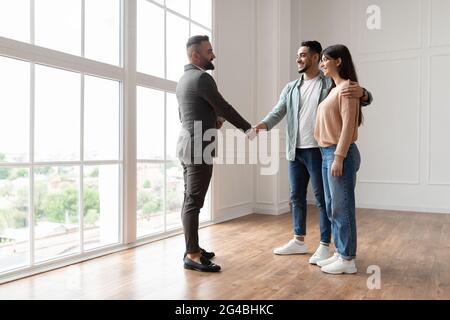 Couple achetant un nouvel appartement, en serrant la main avec Realtor Banque D'Images