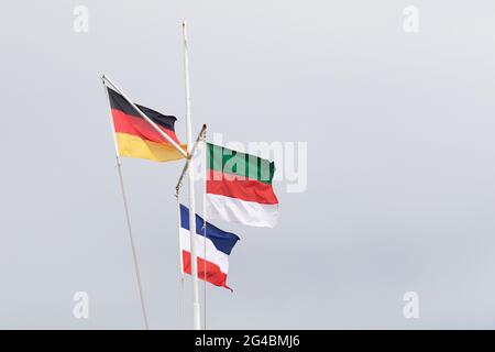 Drapeaux de l'Allemagne, de l'Helgoland et de la Yougoslavie contre un ciel couvert Banque D'Images