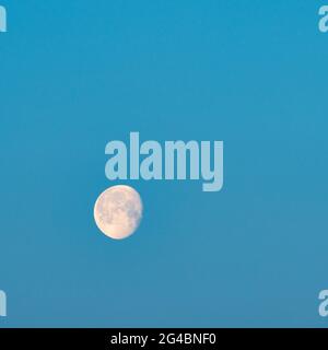 Une photo téléobjectif de la lune au-dessus du Yorkshire du Nord au début d'une journée chaude à la fin du printemps. Photo d'Almscliffe Crag. Banque D'Images