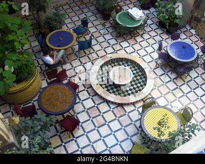 Fez, Maroc - 29 mars 2013: Un homme regardant son téléphone mobile assis dans un patio de design arabe. Banque D'Images